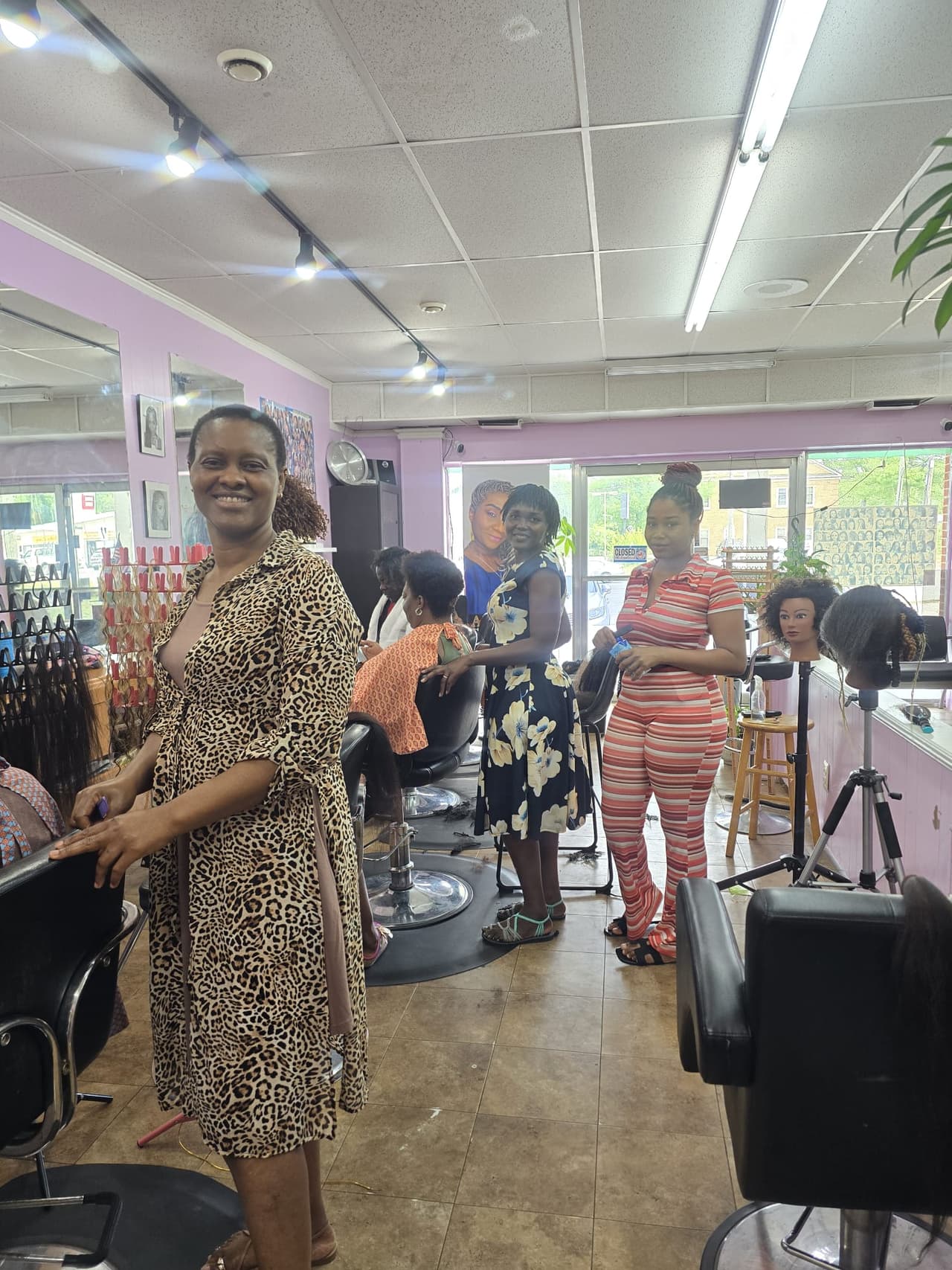 A smiling stylist inside the Akwaba Hair Braiding salon
