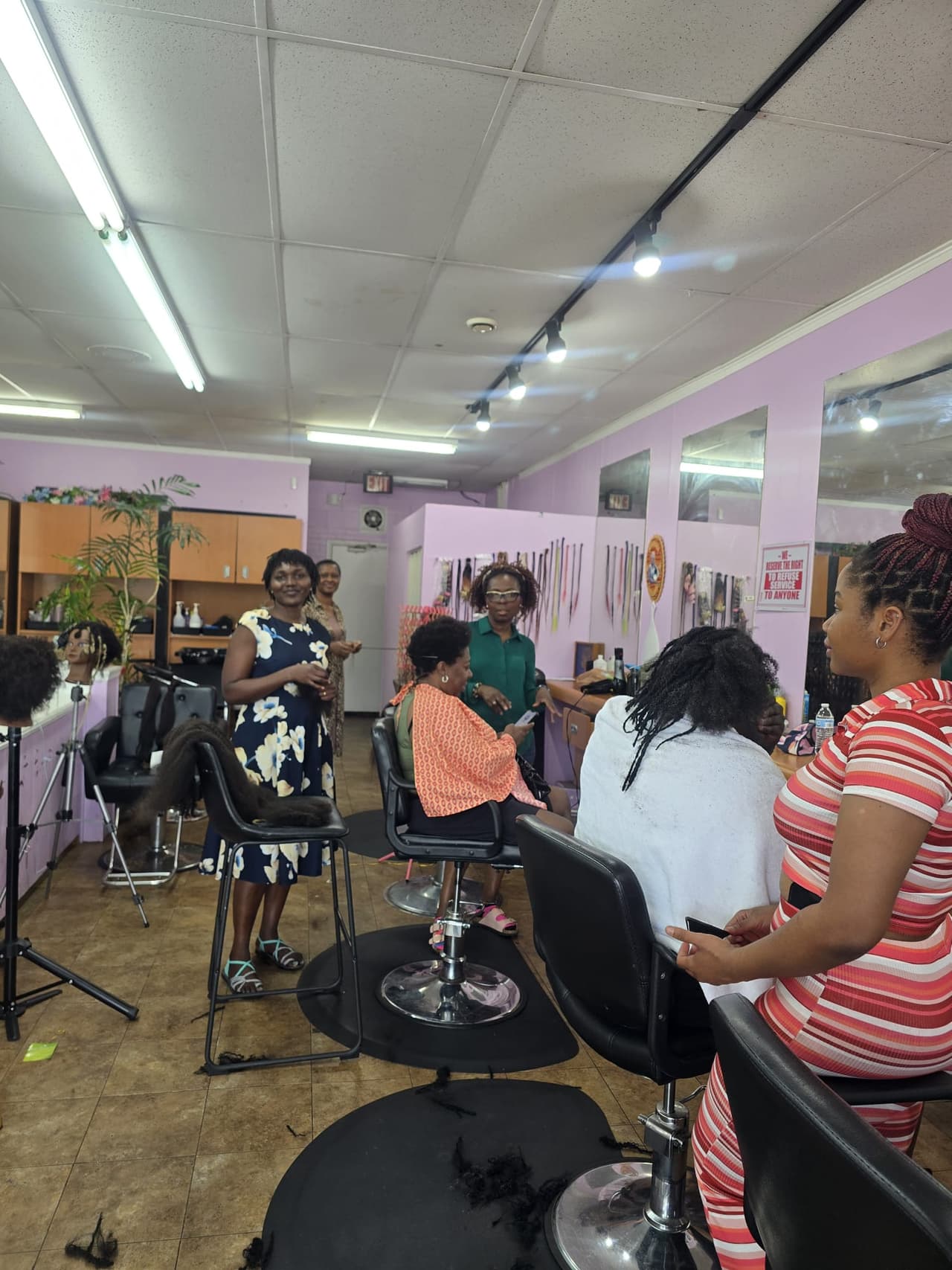 Stylists braiding clients' hair inside the Akwaba salon
