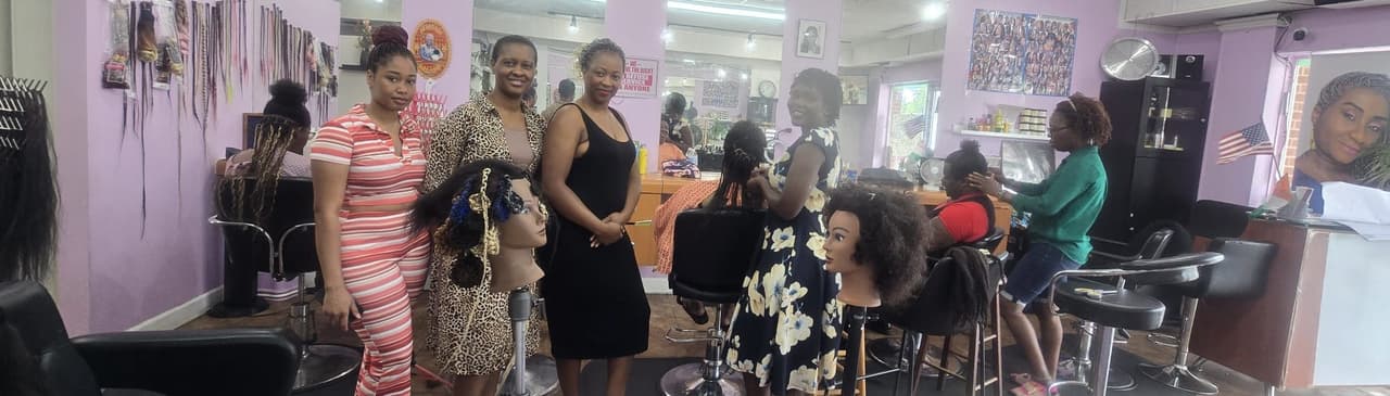 The Akwaba Hair Braiding team together in the salon, among styling stations and braided mannequin displays